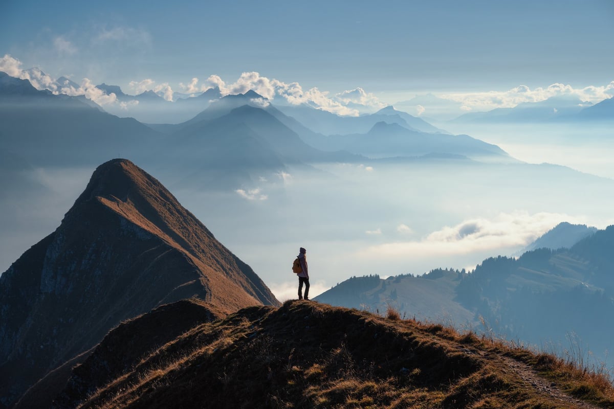 Hiker on a mountain ridge above the clouds at sunset